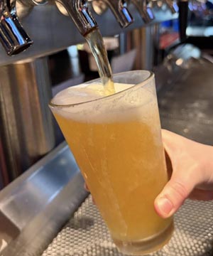 Beer being poured into a frosty pint glass from a tap