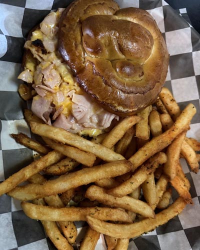 Coach's Corner Fran melt served on a pretzel bun with French fries