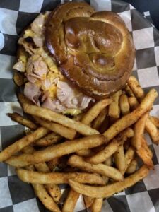 Coach's Corner Fran melt served on a pretzel bun with French fries