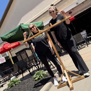 Two ladies posing with a jumbo ring and hook game on the Coach's Corner patio